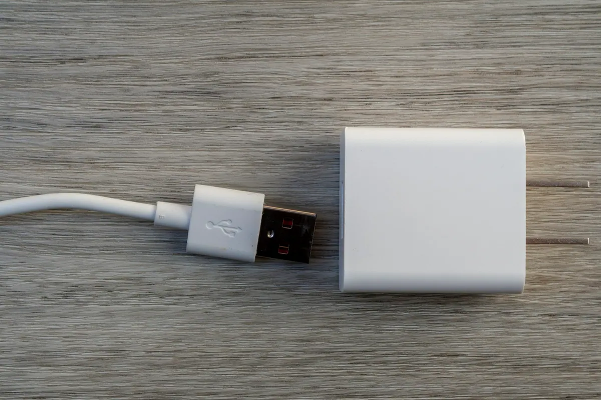 White charging adapter and cable on a wooden surface