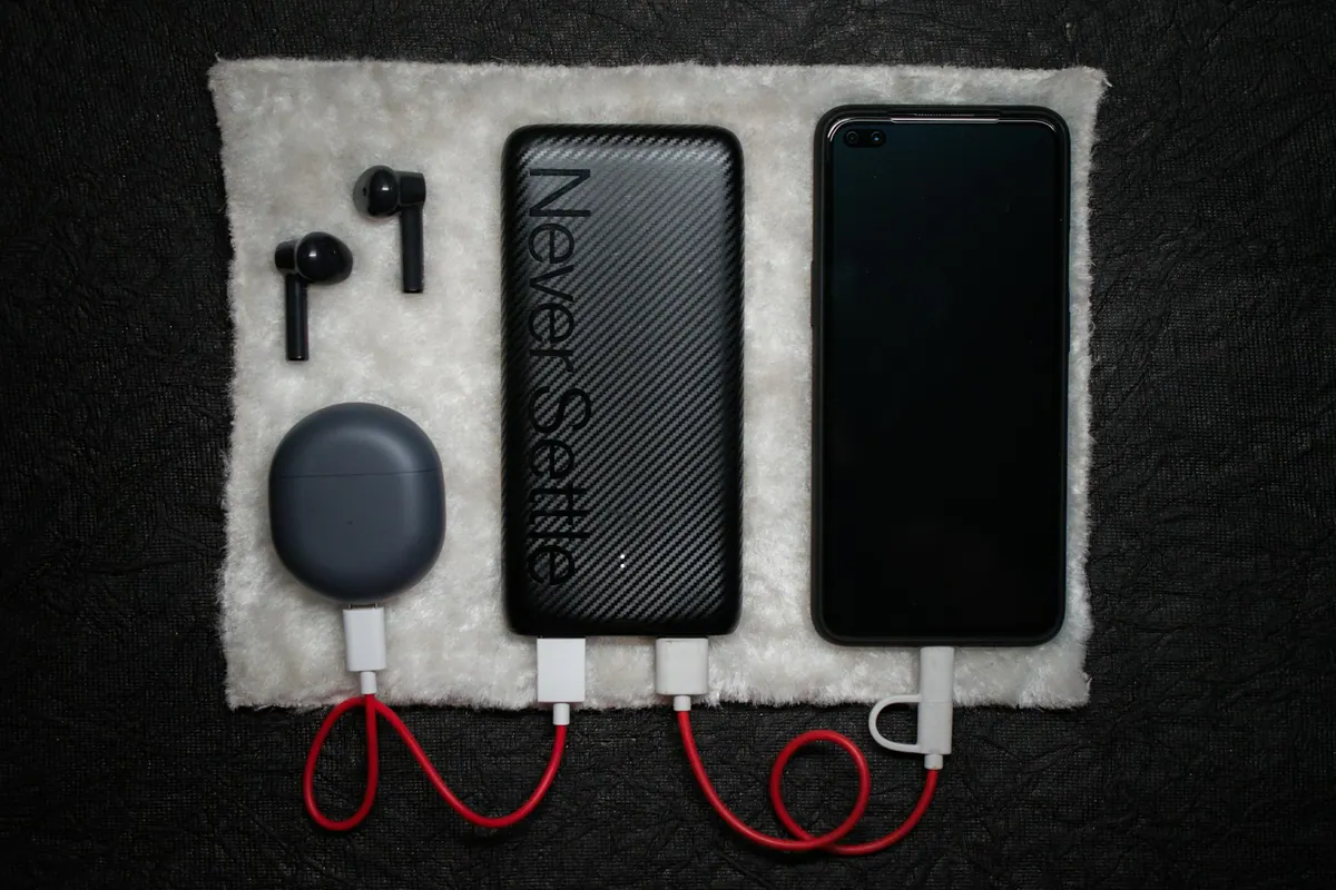 Phone, portable power bank and charging cable arranged on a dark surface