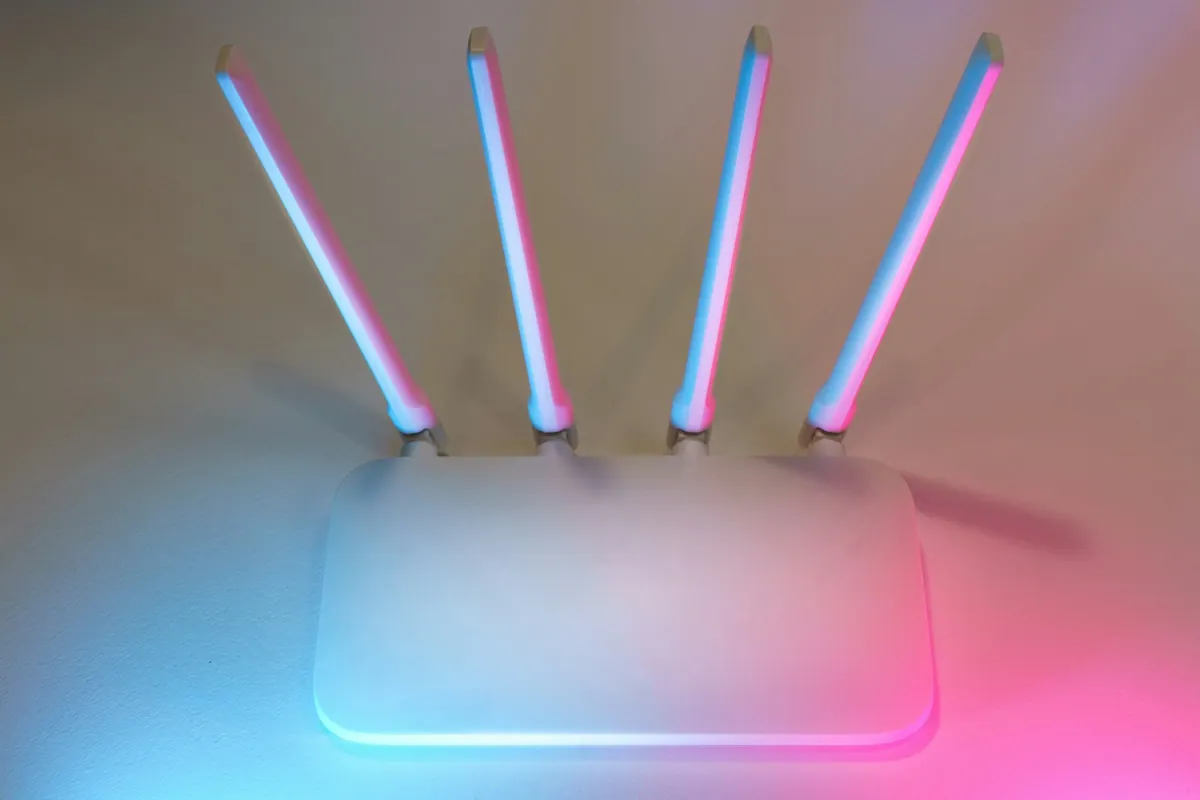 A home Wi-Fi router with upright antennas in colored light