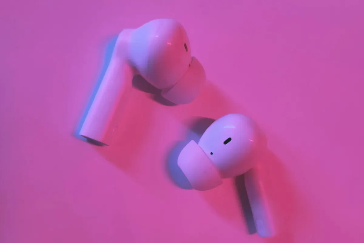 Wireless earbuds arranged on a softly lit pink surface