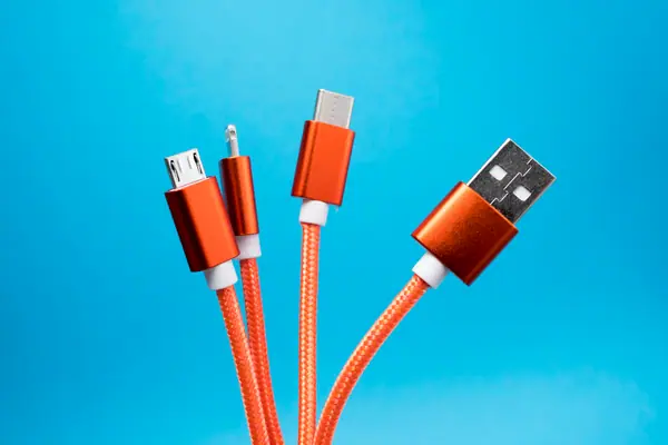 Several orange charging cables with different connectors against blue