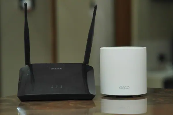 A traditional router and a mesh networking unit on a table